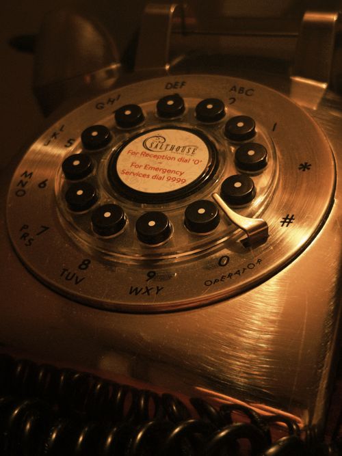 Free Close-up of a classic rotary dial telephone with a warm tone on a wooden background. Stock Photo