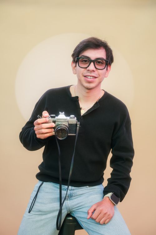 Free Smiling young adult with vintage camera in studio setting, capturing a relaxed and creative vibe. Stock Photo