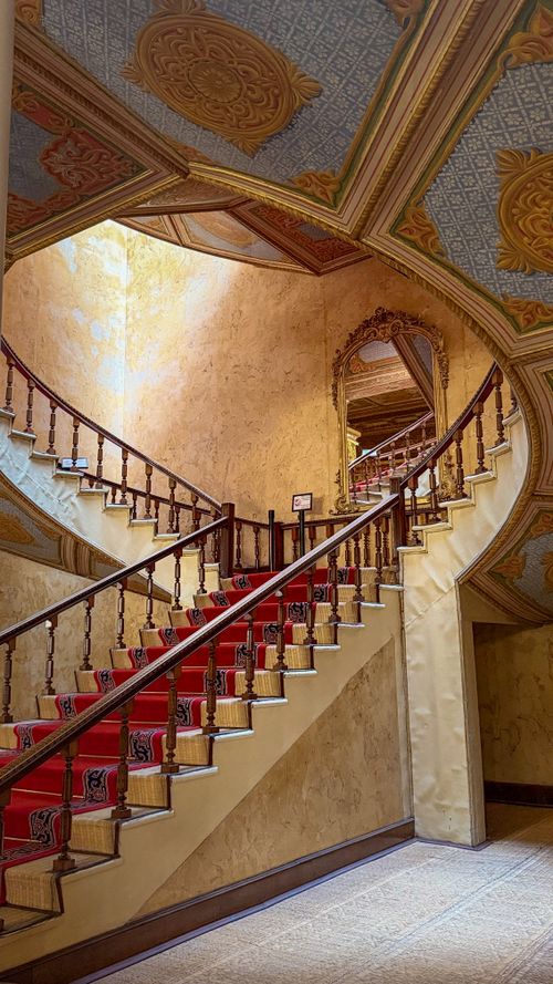 Free Ornate curved staircase with patterned carpet in a historic building interior. Stock Photo