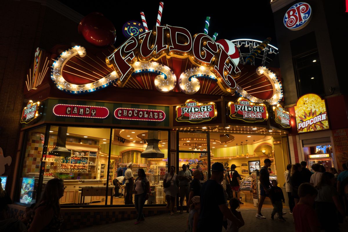Vibrant illuminated candy store exterior bustling with people at night.