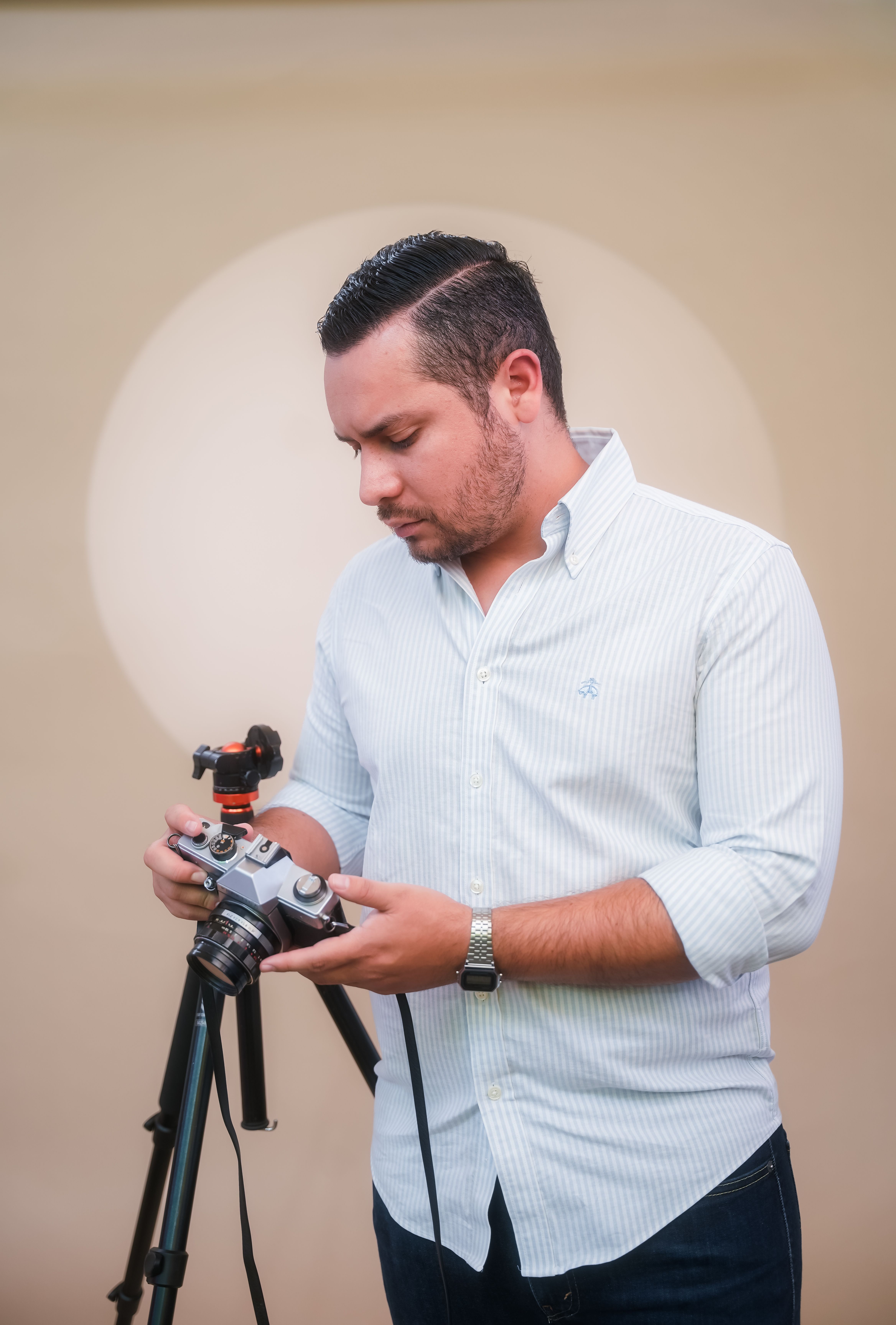 Man adjusting a camera on a tripod with focus on photography equipment.