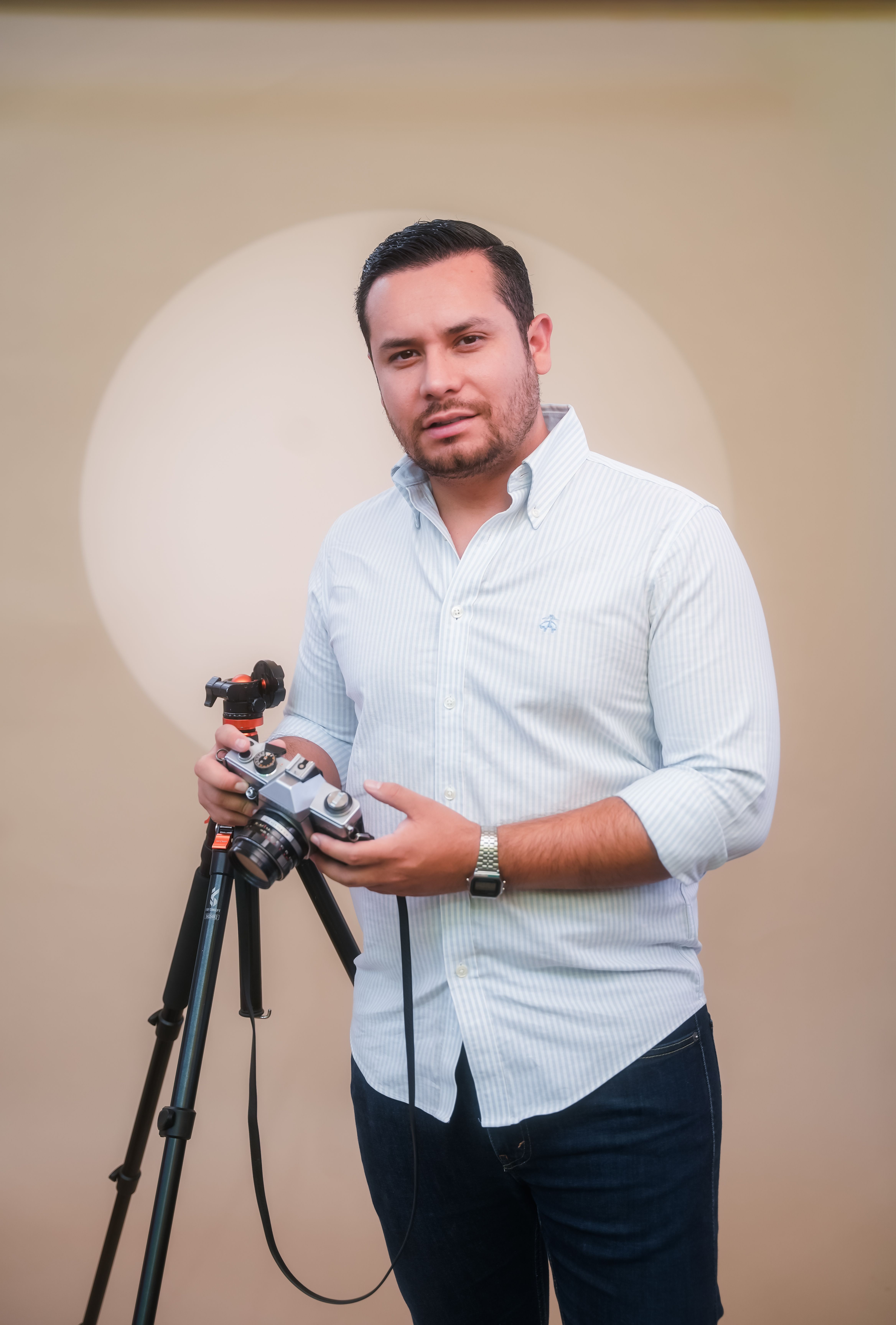 Portrait of a professional photographer with a camera on a tripod in an indoor studio.