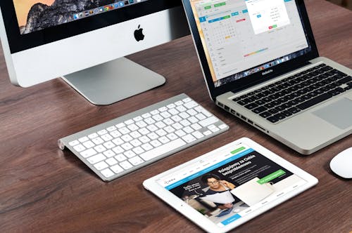 Free A sleek office desk setup featuring Apple devices: iMac, MacBook, and iPad. Stock Photo