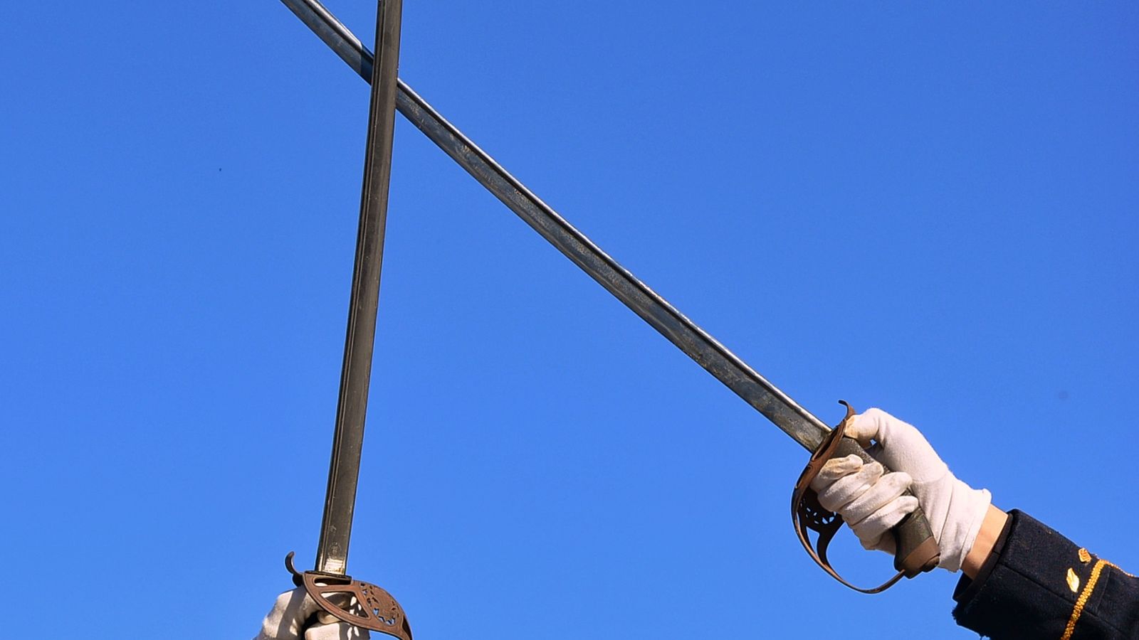 Two swords crossed in a clash against a clear blue sky, a real stock photo of a sword duel chosen as a nod to the blade fights in Phantom Blade Zero