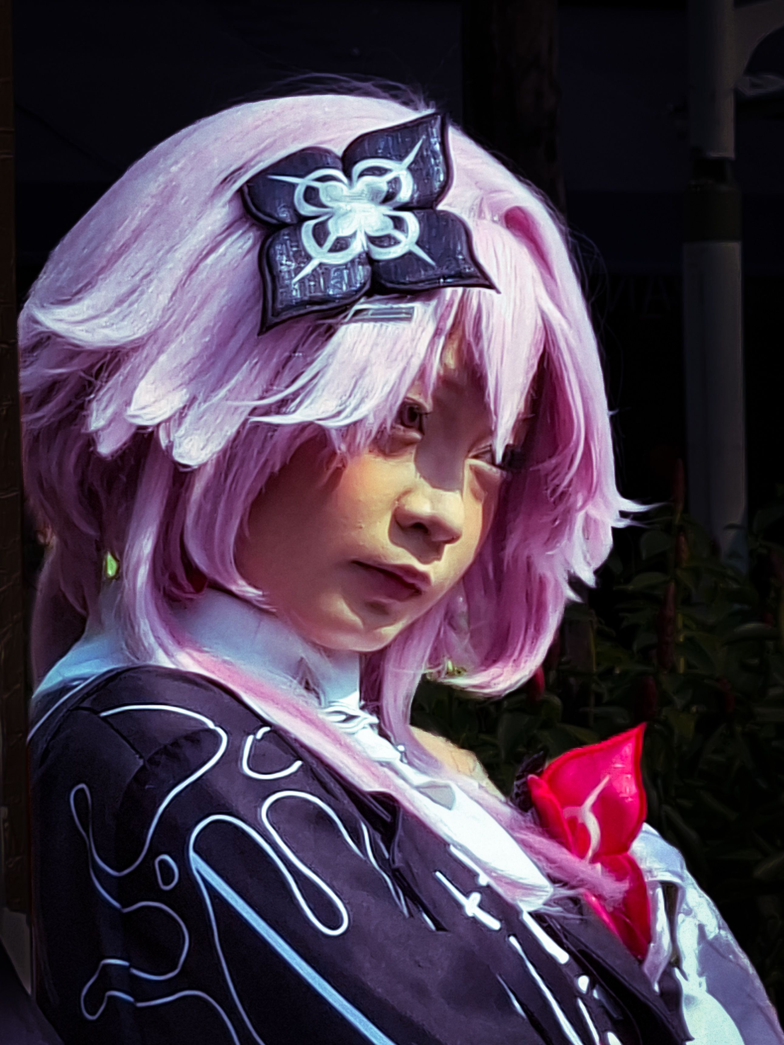 Portrait of a person in cosplay with a pink wig and artistic costume, highlighting creativity.