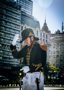 Man in historical military uniform poses in urban area with classic architecture.