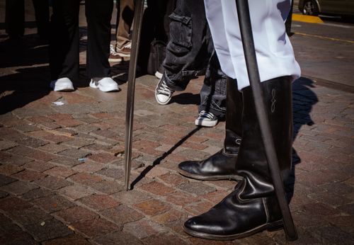 Free Close-up of a street performer wearing traditional boots, standing on cobblestones with a staff. Stock Photo