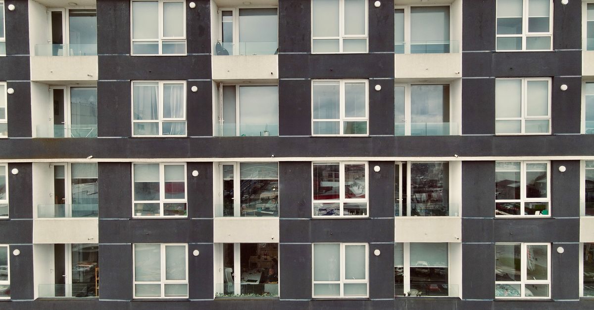 Symmetrical facade of a modern apartment building with balconies and large windows.