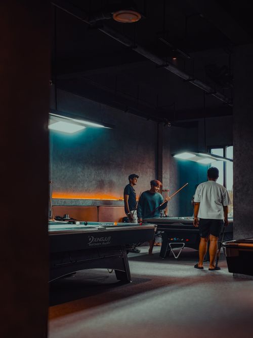 Free Group of friends enjoying a game of billiards in a dimly lit, modern room. Stock Photo
