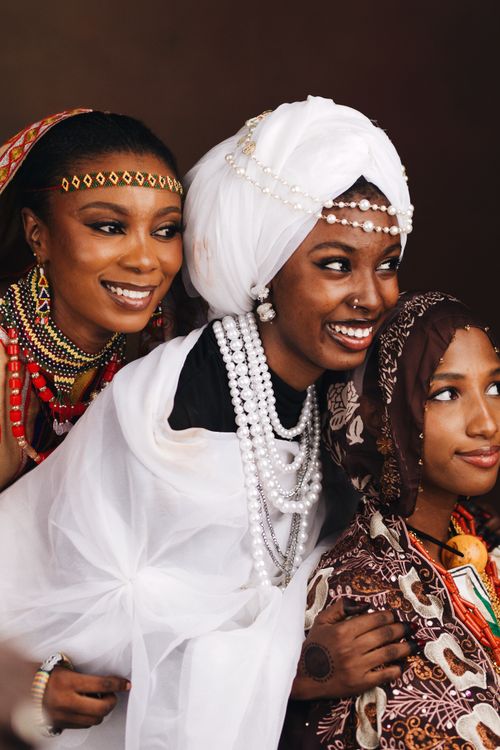 Free Three African women in vibrant traditional clothing and accessories, smiling warmly. Stock Photo