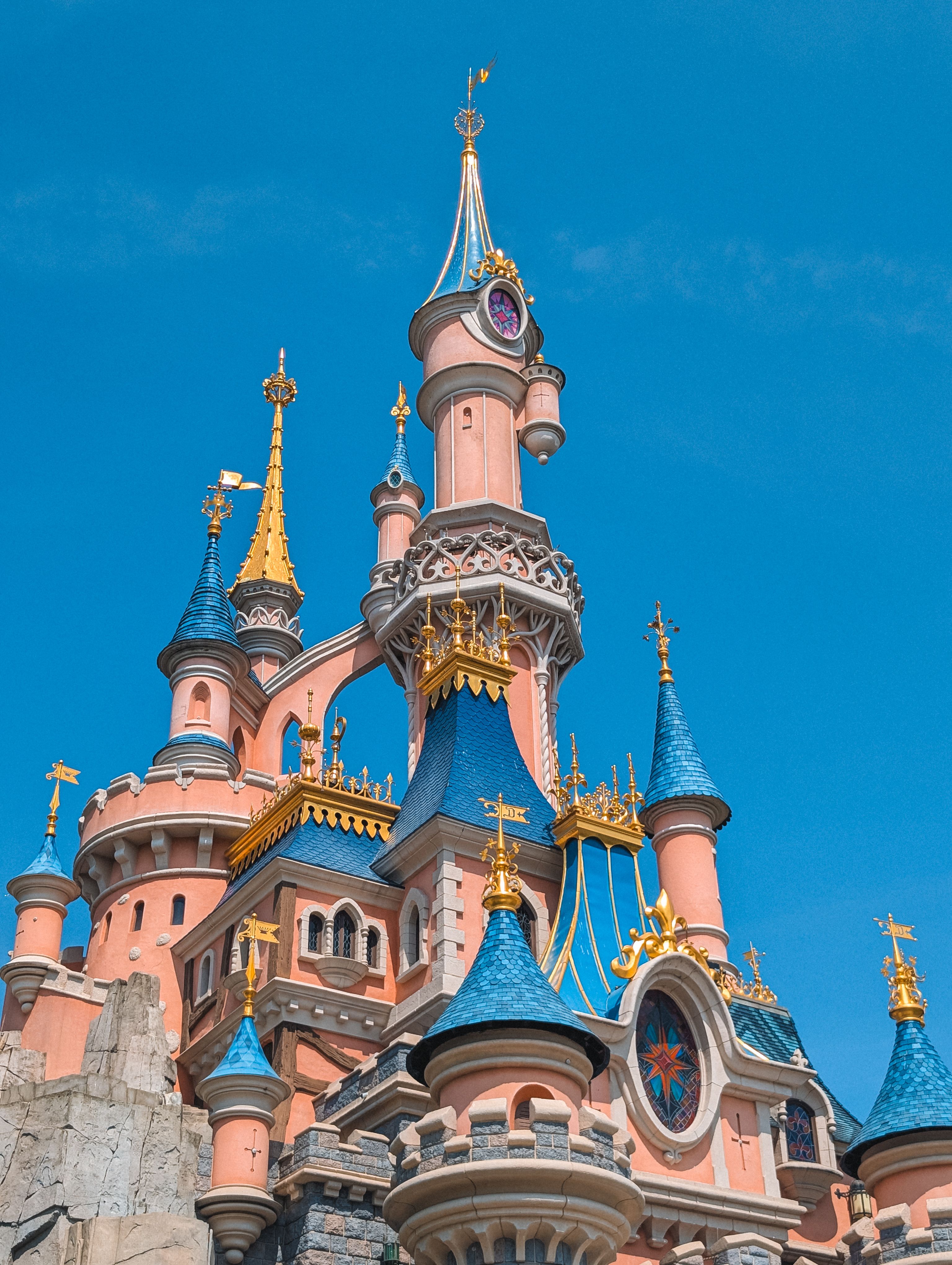 Vibrant Sleeping Beauty Castle at Disneyland Paris with clear blue sky.