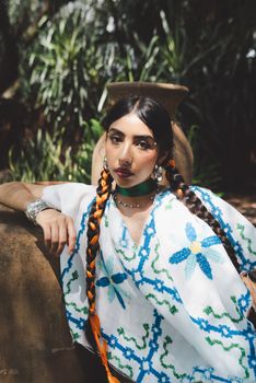 Woman in traditional attire with braided hair, posing outdoors.