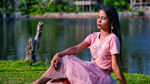 Free A serene portrait of a woman in pink against a tranquil lake backdrop. Stock Photo