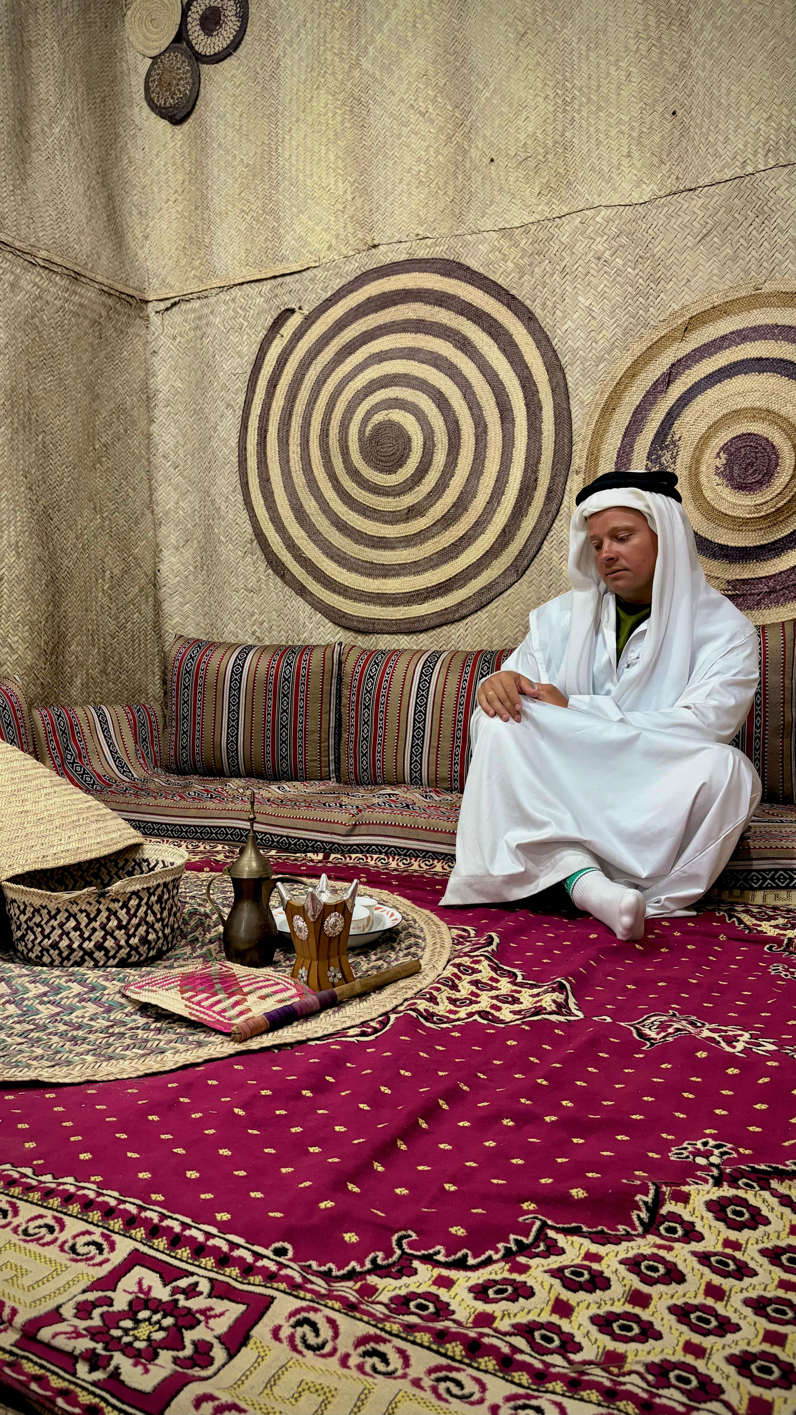 A man in traditional attire enjoys tea inside a traditional Emirati setting in Fujairah, UAE.