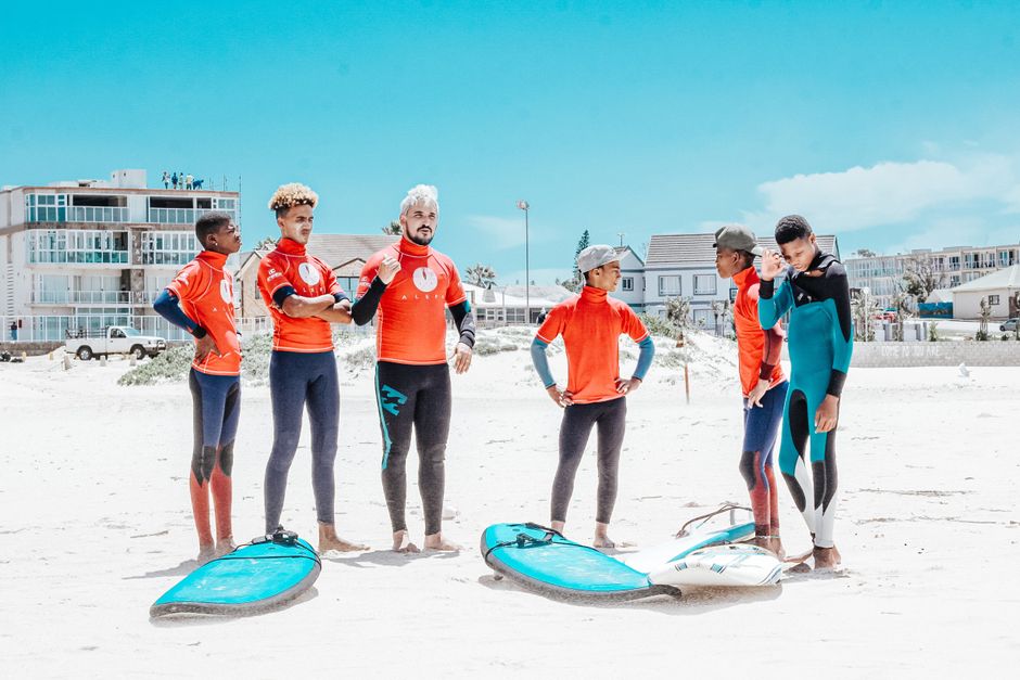Group of young men preparing for surfing lessons on Jeffreys Bay beach in South Africa.