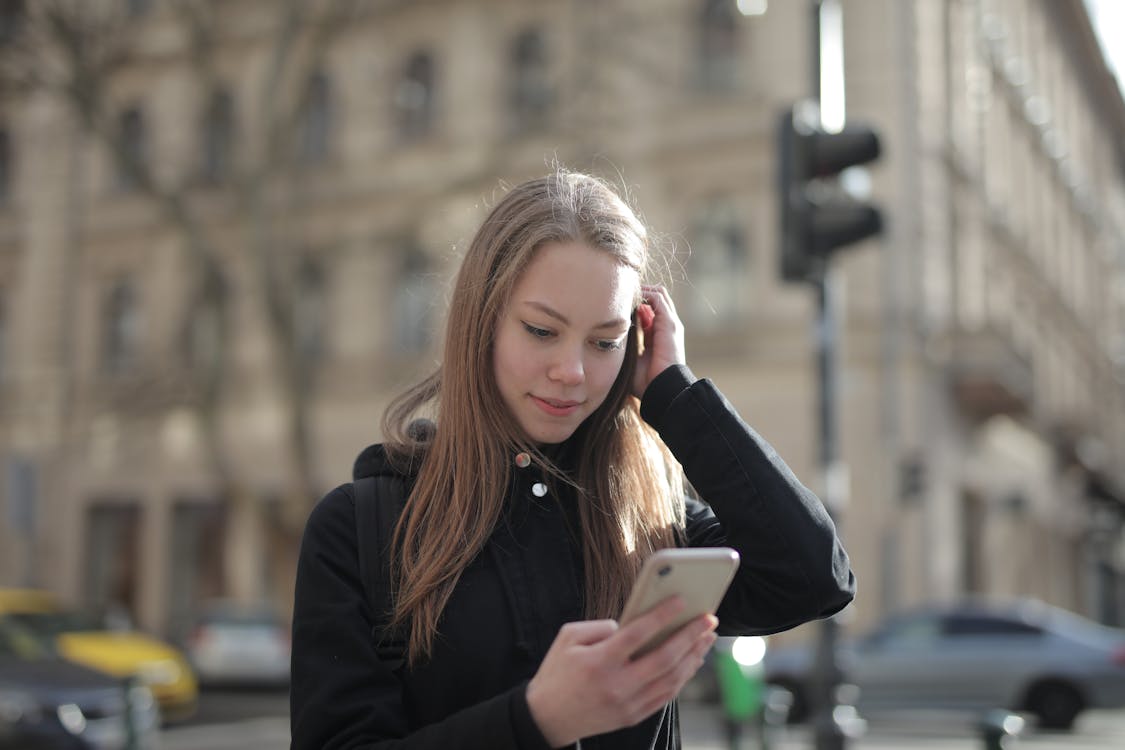 Free Woman in Black Jacket Holding Smartphone Stock Photo