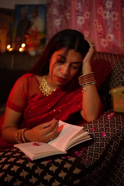 Free Woman in traditional attire reads a book by candlelight, creating a contemplative and serene atmosphere. Stock Photo