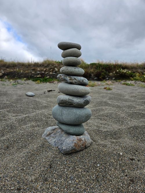 Free Stone tower stacked on a calm beach setting with cloudy skies. Stock Photo