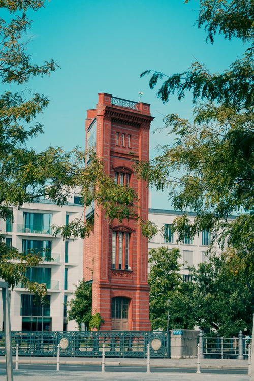 Free A striking red brick tower set amidst modern architecture in Berlin, offering a unique blend of historic and contemporary styles. Stock Photo