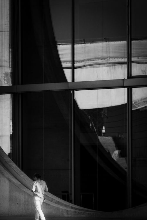 Free Black and white artistic shot of modern architecture featuring reflections and a solitary person. Stock Photo