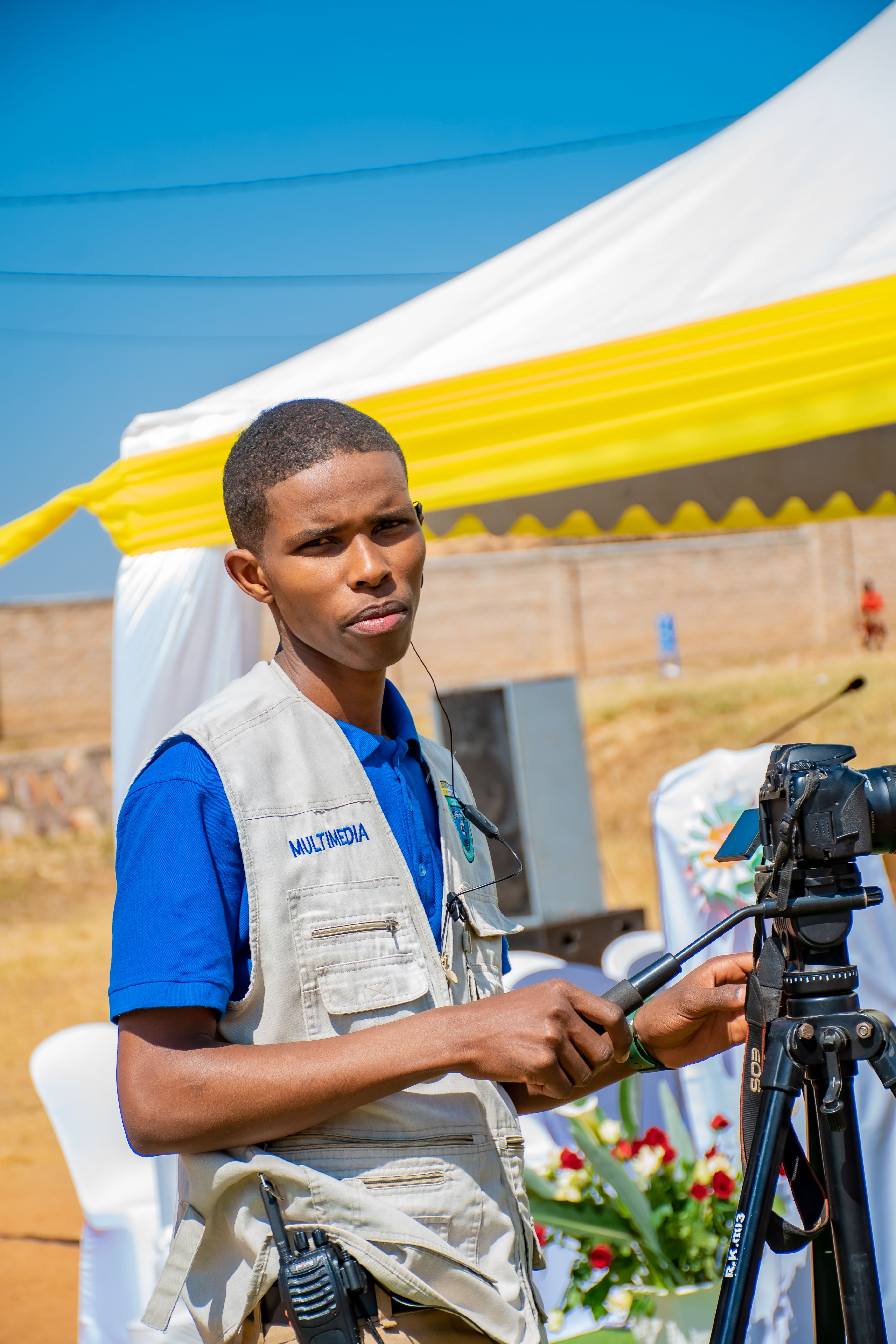 Young videographer using camera at an outdoor event during the day.