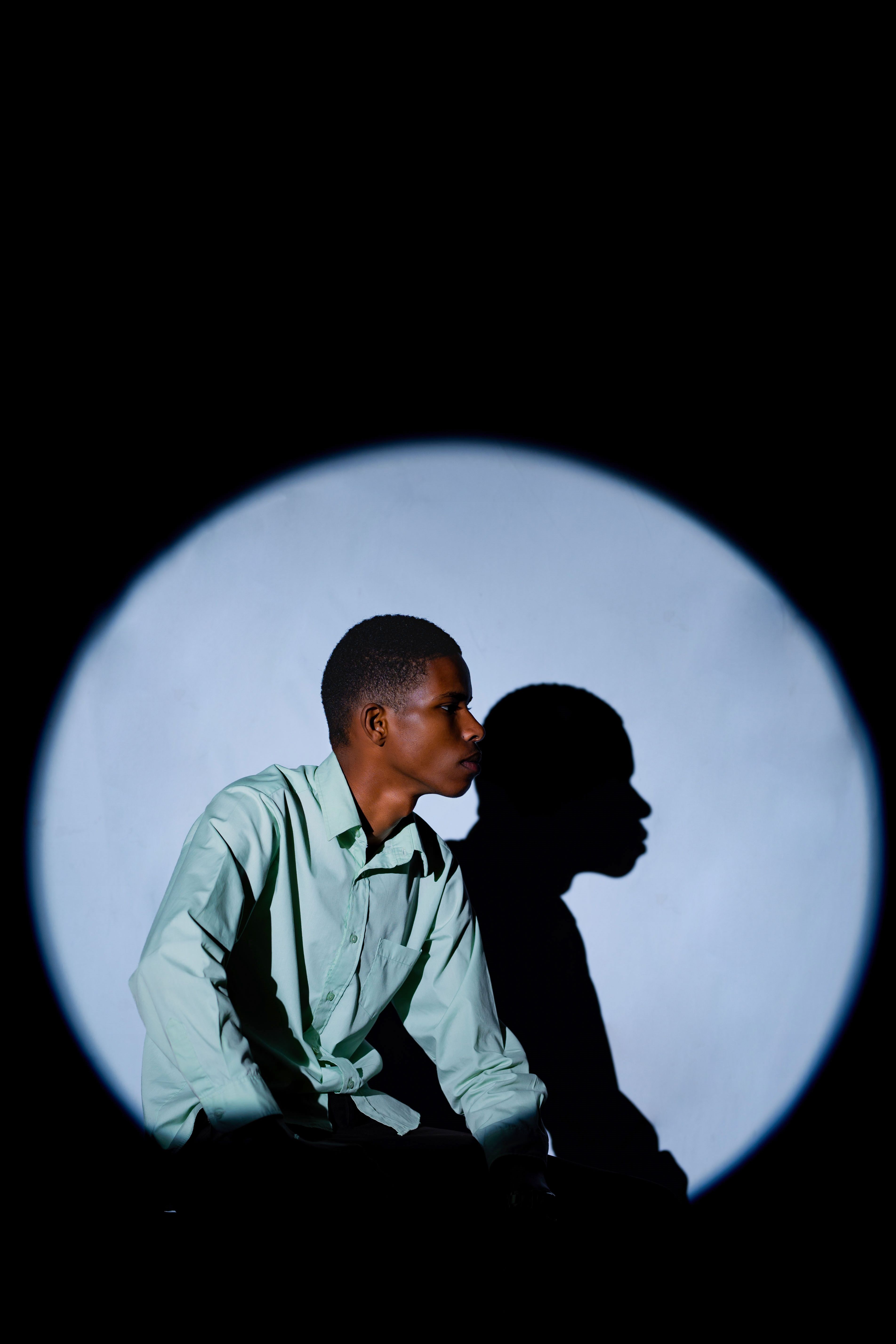 Captivating portrait featuring dramatic shadow and artistic lighting on a black background.