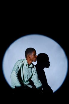Captivating portrait featuring dramatic shadow and artistic lighting on a black background.