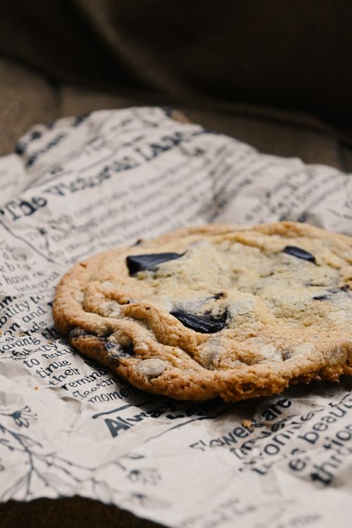 Free Delicious chocolate chip cookie placed on newspaper-style wrapping paper. Stock Photo