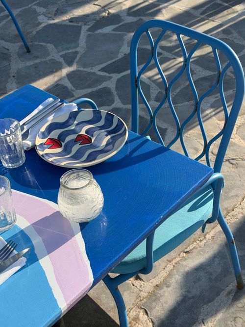 Free A vibrant outdoor cafe setting with a blue-themed decor, featuring a patterned plate and colorful table. Stock Photo