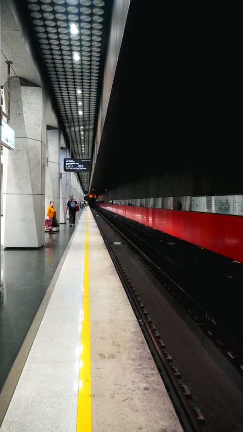 Free Wide view of a sleek subway platform with people waiting for a train. Stock Photo
