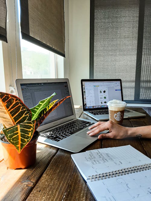 在棕色的木桌上使用macbook的人