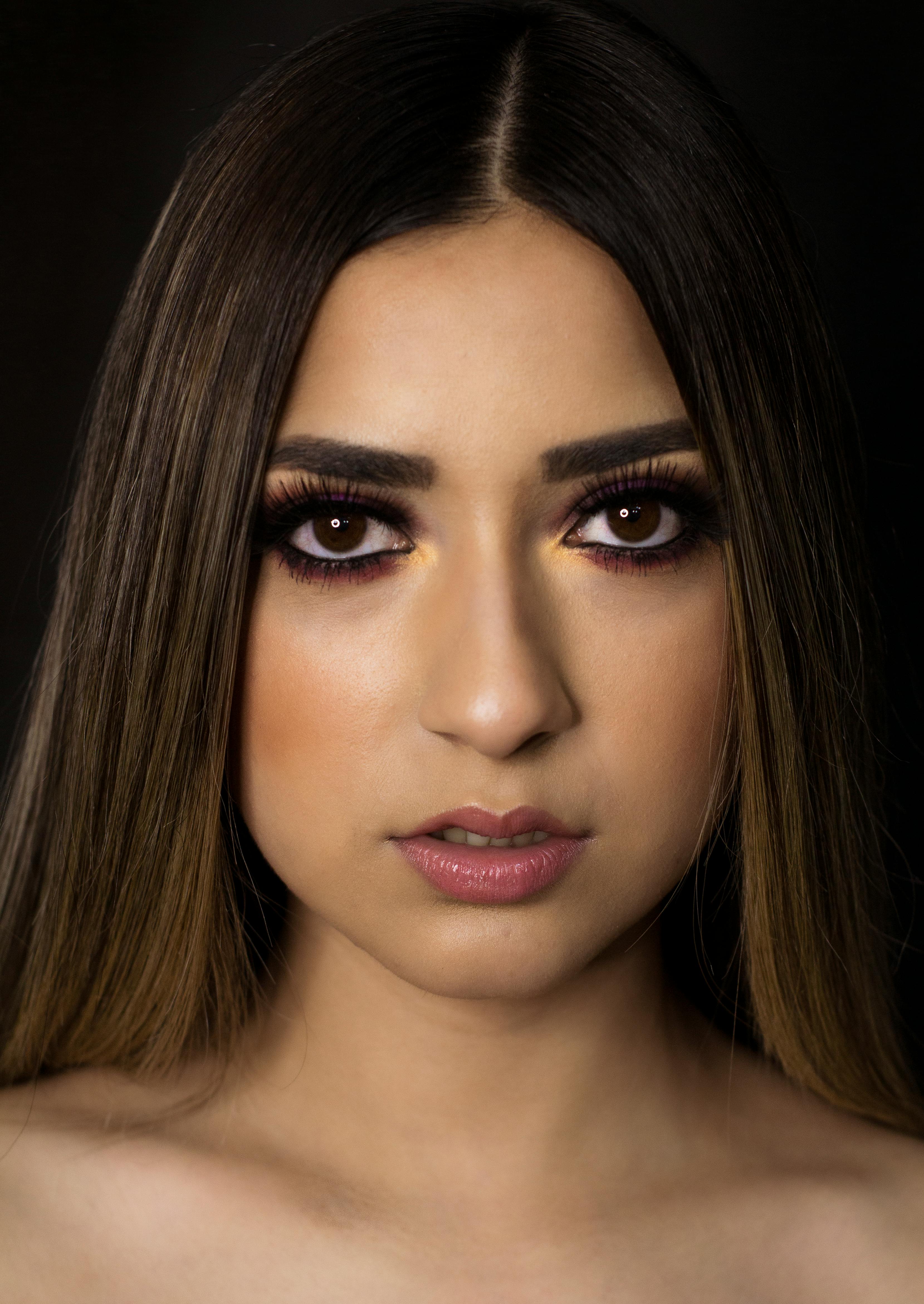 一个女人的特写肖像，迷人的眼妆和深色背景，展示了优雅和风格