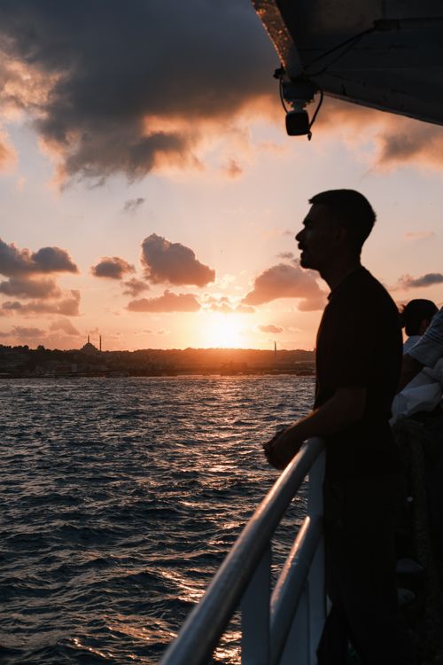 Free A man stands in silhouette on a ferry in Istanbul, capturing a stunning Bosphorus sunset. Stock Photo