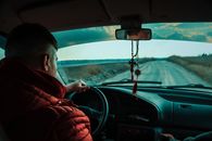 黄昏时分，一名男子驾车行驶在乡村道路上，展现着旅行与探索