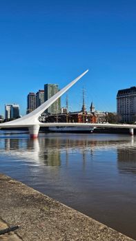 Iconic skyline with Puente de la Mujer in Buenos Aires reflecting in the river.