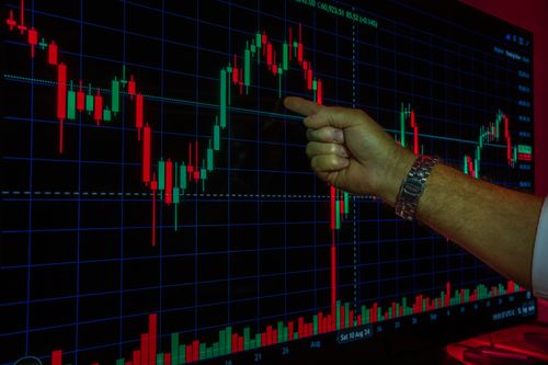Free A hand analyzing a financial graph on a digital screen, highlighting stock market trends and data. Stock Photo