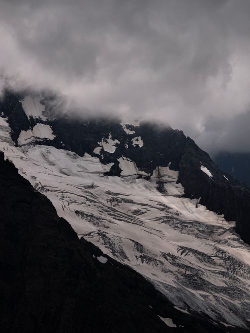Free A majestic snowy mountain peak under dark, moody clouds, showcasing nature's dramatic beauty. Stock Photo