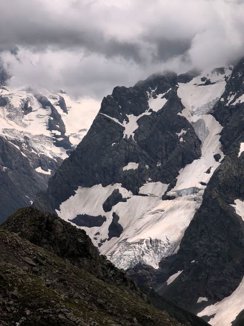 Free Majestic snow-capped mountain peaks under dramatic cloud cover, creating a moody landscape. Stock Photo