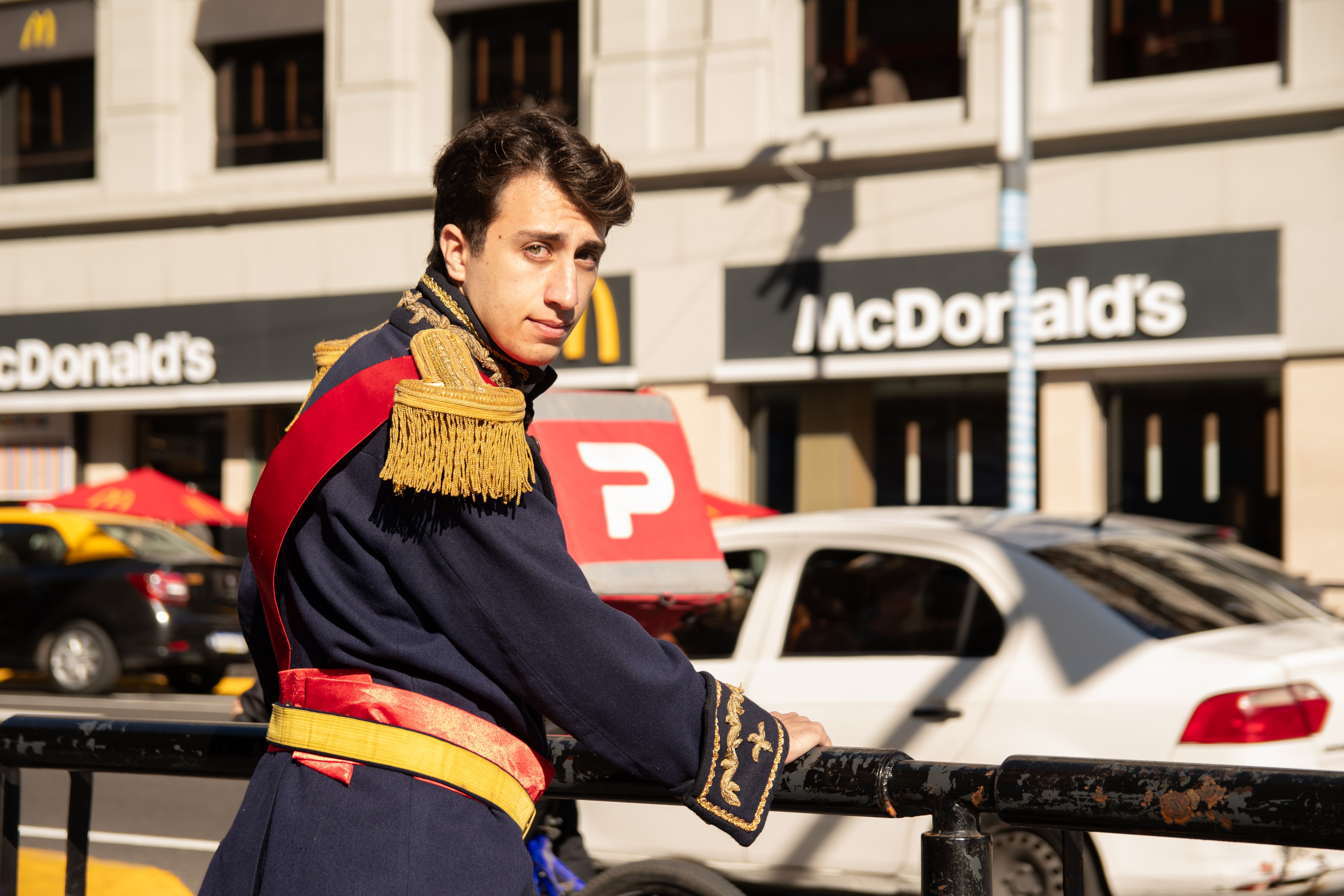 A young man in historical costume poses near a McDonald's in an urban setting.