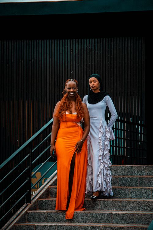 Free Two fashionable women in bright dresses descend a staircase, showcasing urban elegance in Rwanda. Stock Photo