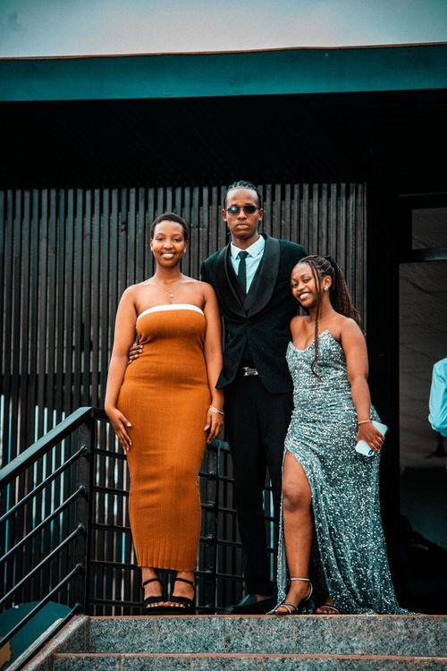 Free Young adults in stylish formal wear pose confidently outside a modern building in Rwanda. Stock Photo