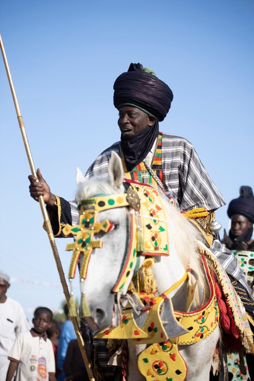 Free A horseman in traditional attire participates in a vibrant cultural parade under the clear blue sky. Stock Photo