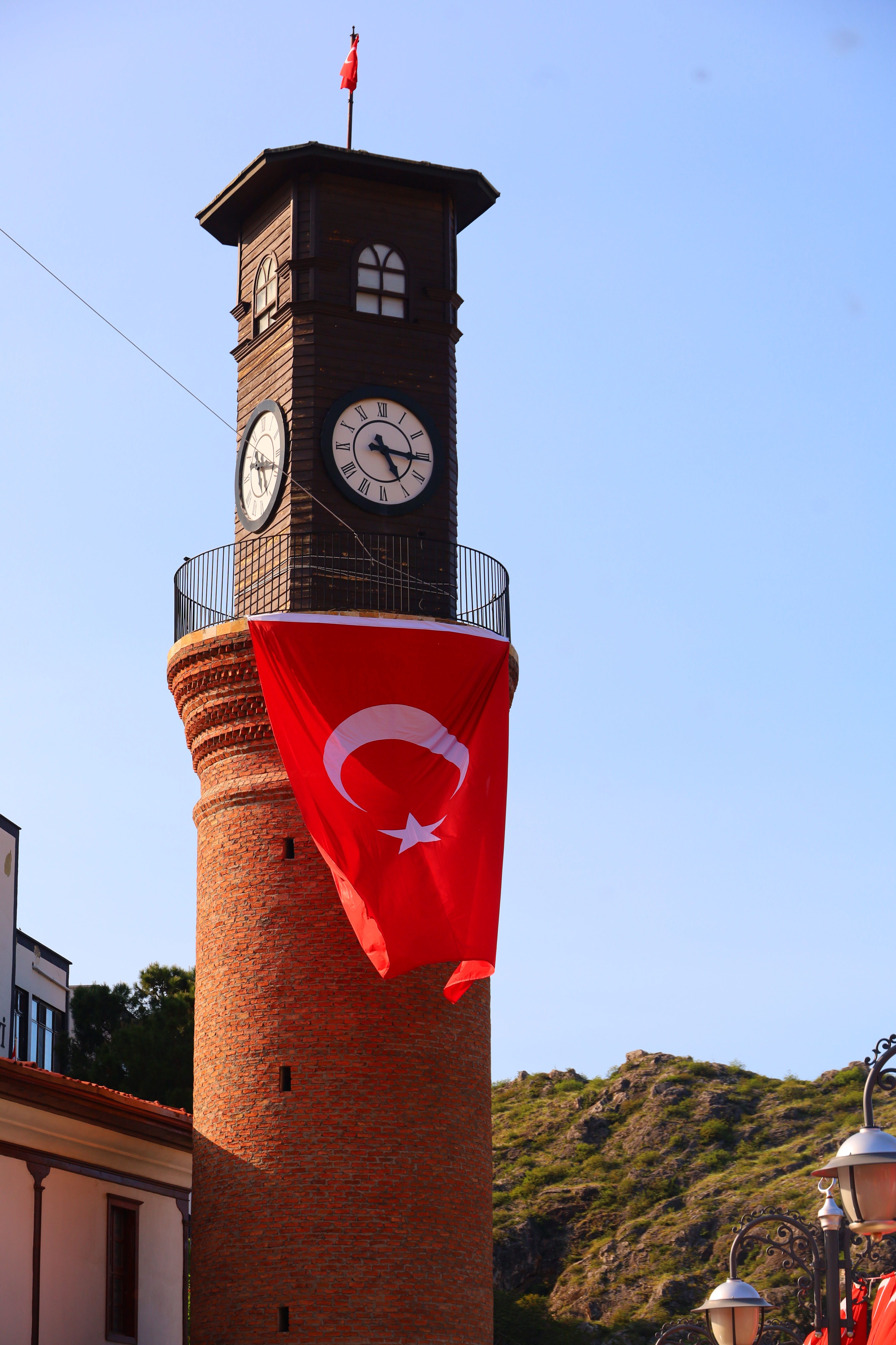 Historic clock tower featuring a Turkish flag under a clear blue sky.