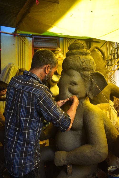 Free Artisan sculpting a clay Ganesha statue, capturing the essence of Ganesh Chaturthi in Nagpur, India. Stock Photo