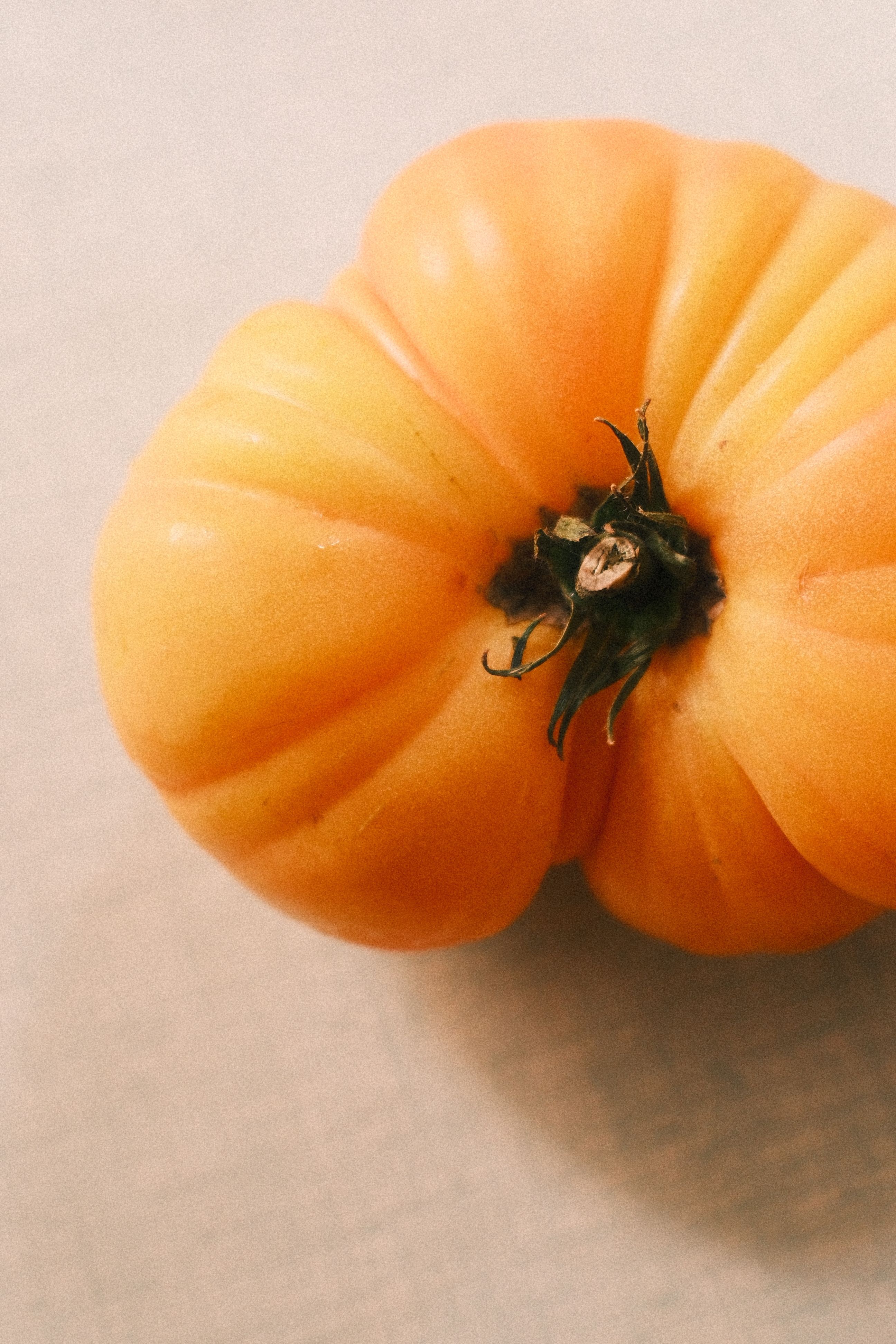 High-quality image capturing a fresh yellow heirloom tomato on a light background.