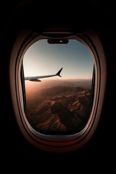 Scenic view from airplane window of mountains at sunset, capturing the beauty of Utah.
