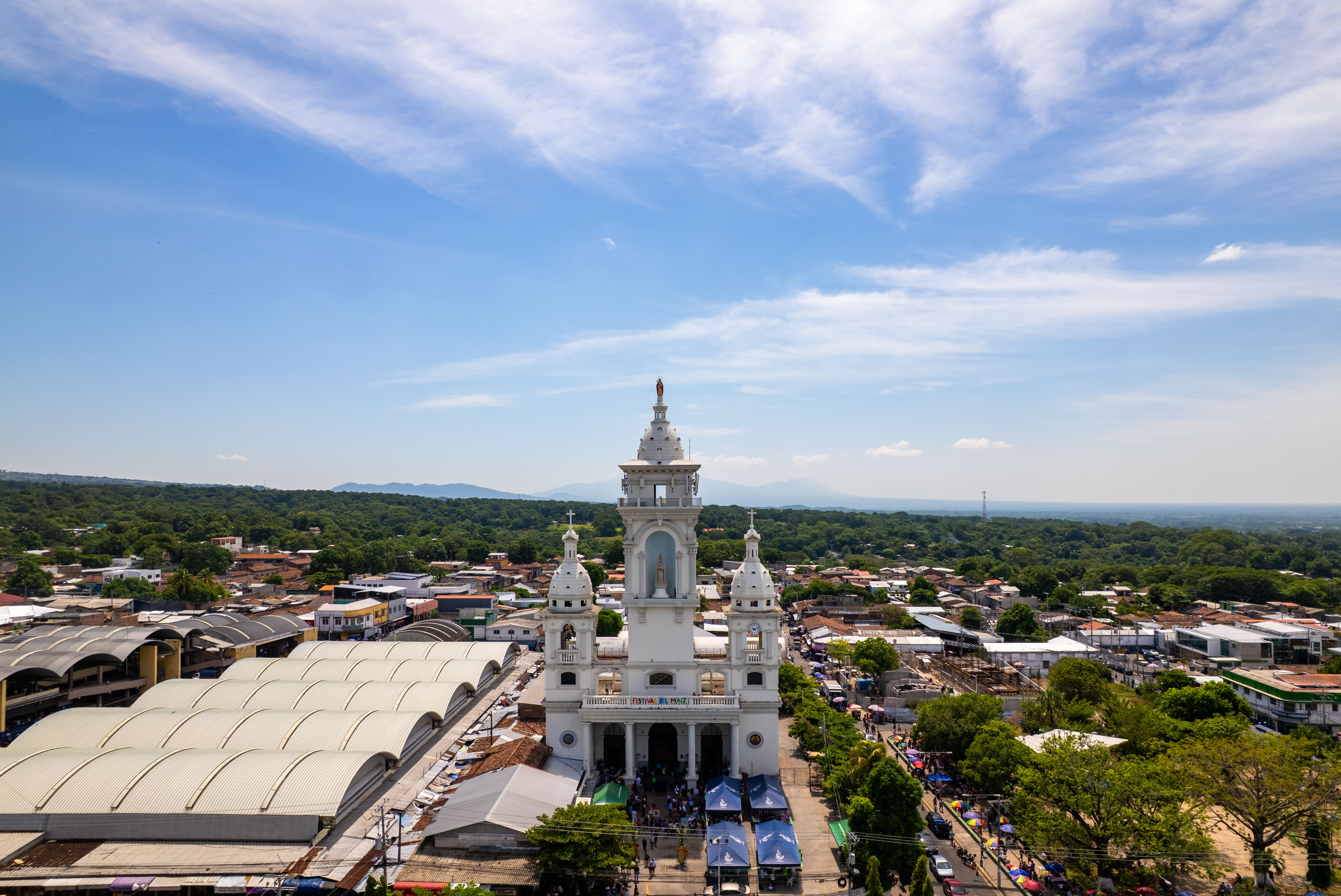 Scenic aerial shot of a church in Zacatecoluca surrounded by lush greenery and clear skies.