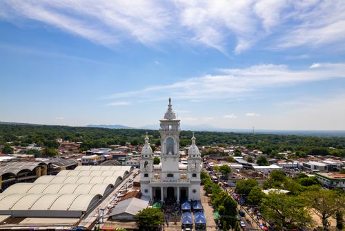 Free Scenic aerial shot of a church in Zacatecoluca surrounded by lush greenery and clear skies. Stock Photo