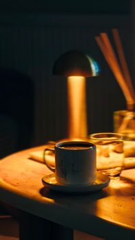 A warm and cozy scene with coffee, lamp light, and decor creating a relaxed ambiance.