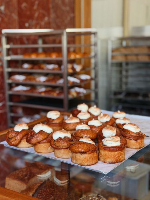 Free Delicious freshly baked pastries with cream cheese frosting, beautifully arranged in a bakery display. Stock Photo